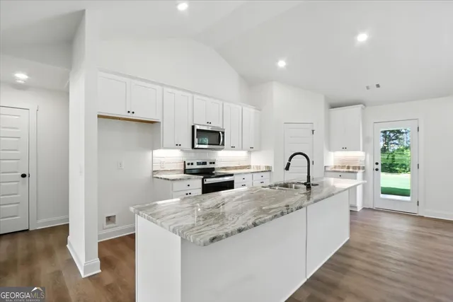 a kitchen with cabinets wooden floor and stainless steel appliances