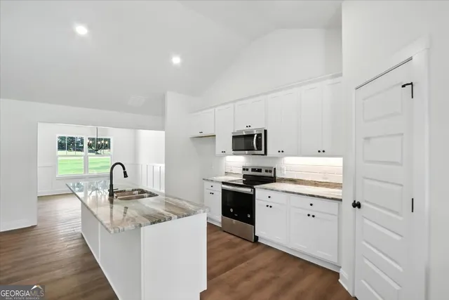 a kitchen with granite countertop a refrigerator stove top oven and sink