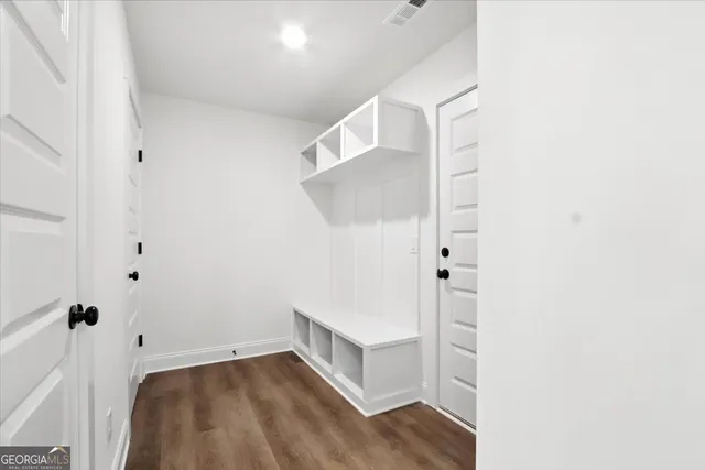 a view of empty room with wooden floor and kitchen view