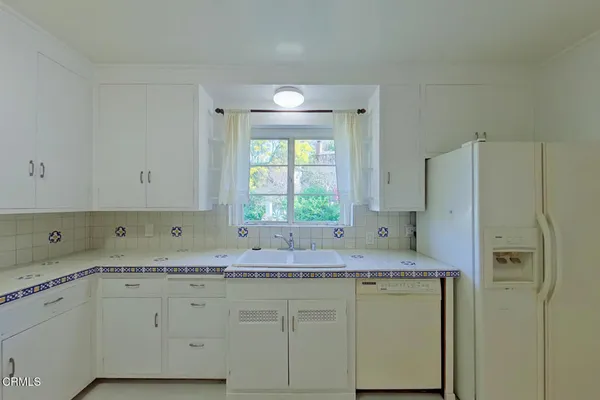 a kitchen with granite countertop a sink cabinets and stainless steel appliances