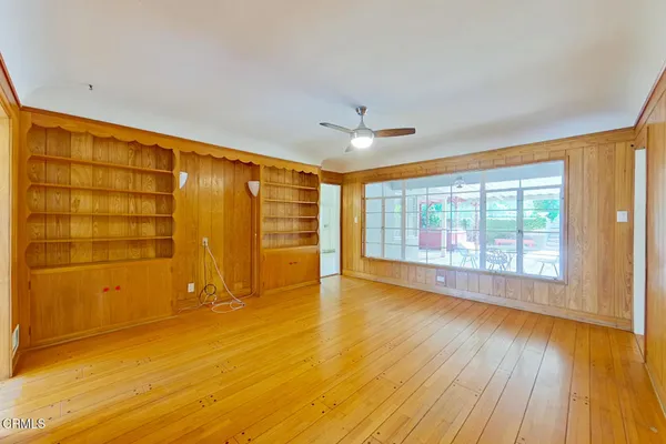 a view of empty room with wooden floor and fan