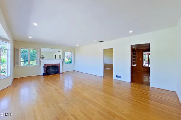 a view of an empty room with window and wooden floor