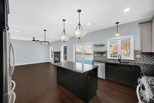 a large kitchen with granite countertop a sink dishwasher a stove and a dining table with wooden floor