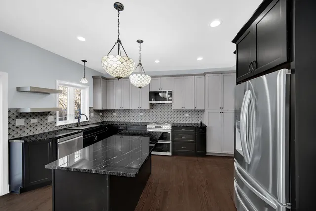 a kitchen with stainless steel appliances granite countertop a sink a stove and a refrigerator