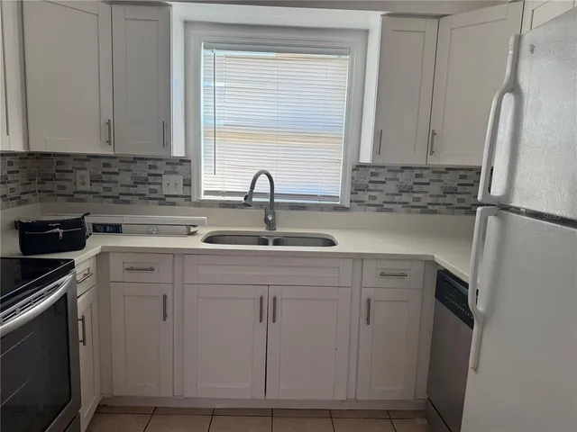 a kitchen with white cabinets and a refrigerator