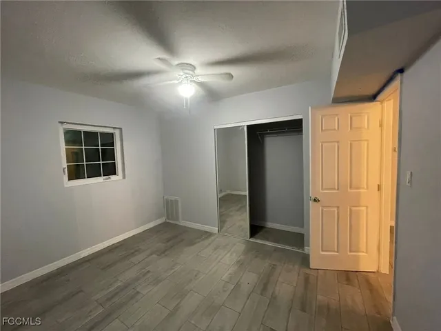 a view of empty room with wooden floor and fan