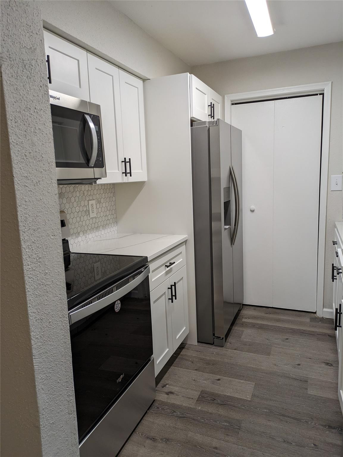 949 Riverside Drive, Unit 411 Coral Springs, FL 33071 - Photo 5 of 15 a kitchen with white cabinets and stainless steel appliances