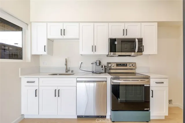a kitchen with white cabinets stainless steel appliances and sink