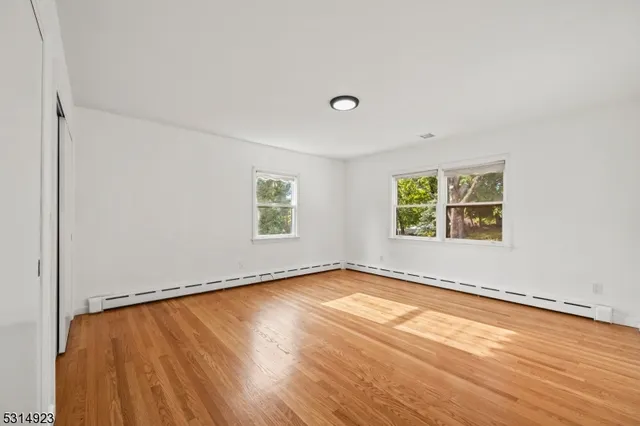 a view of a big room with wooden floor and windows