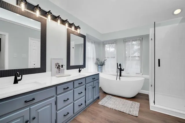 a bathroom with a double vanity sink mirror and bathtub