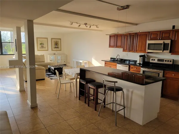 a kitchen with stainless steel appliances a stove a sink a oven a dining table and chairs