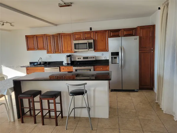 a kitchen with stainless steel appliances granite countertop a refrigerator a stove a sink a dining table and chairs