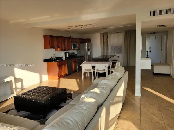 a living room with stainless steel appliances furniture a rug and a view of kitchen