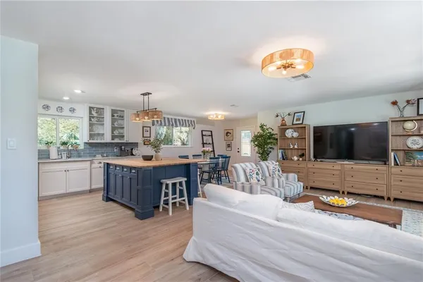 a living room with furniture kitchen view and a large window