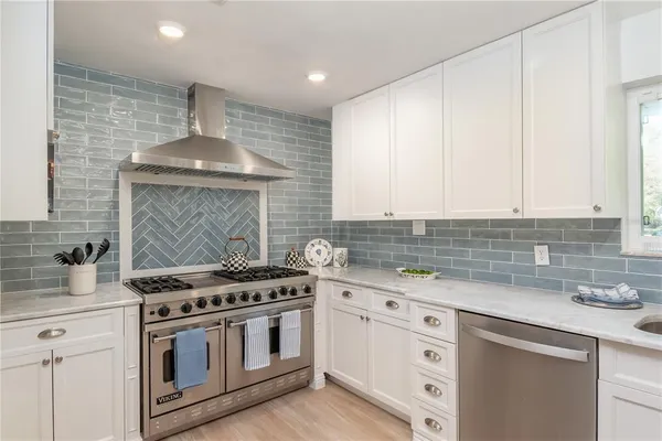 a kitchen with stainless steel appliances a stove a sink and white cabinets