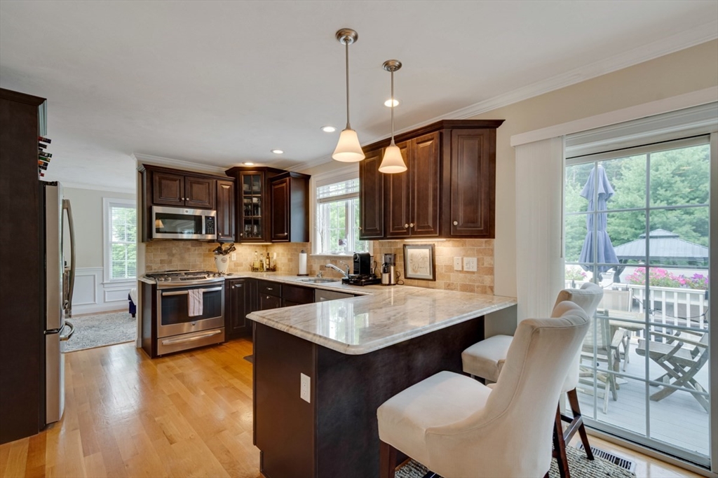 4 Rhodes Drive, Unit 4 Berlin, MA 01503 - Photo 11 of 30 a kitchen with stainless steel appliances granite countertop a stove top oven a sink dishwasher a dining table and chairs with wooden floor