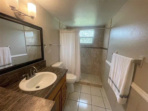 a bathroom with a sink a toilet a mirror and shower