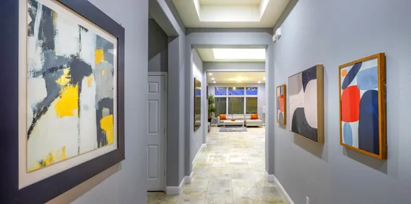 a hallway with painting on the wall and a large window