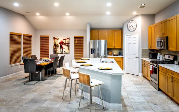 a open kitchen with stainless steel appliances granite countertop a stove top oven a sink a dining table and chairs