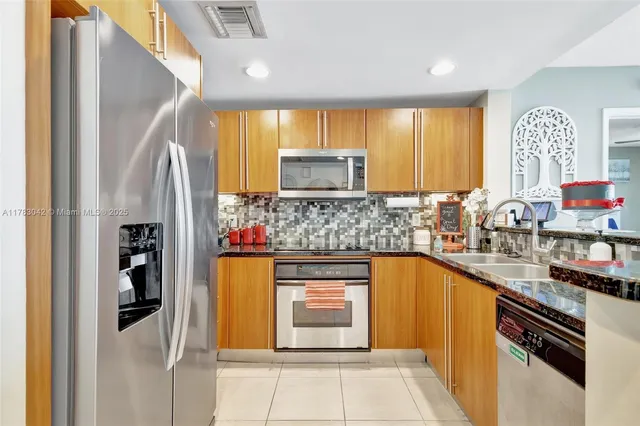 a kitchen with stainless steel appliances granite countertop a refrigerator and a stove top oven