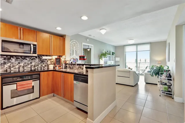 a kitchen with stainless steel appliances granite countertop a stove top oven a sink dishwasher and white cabinets with wooden floor