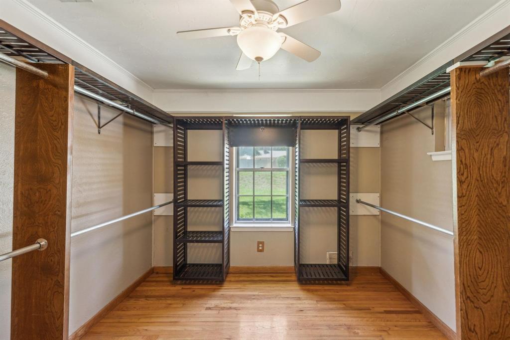 412 West Spinner Road DeSoto, TX 75115 - Photo 12 of 13 Spacious closet featuring wood-finish flooring, a window, built-in shelving, and multiple hanging rods