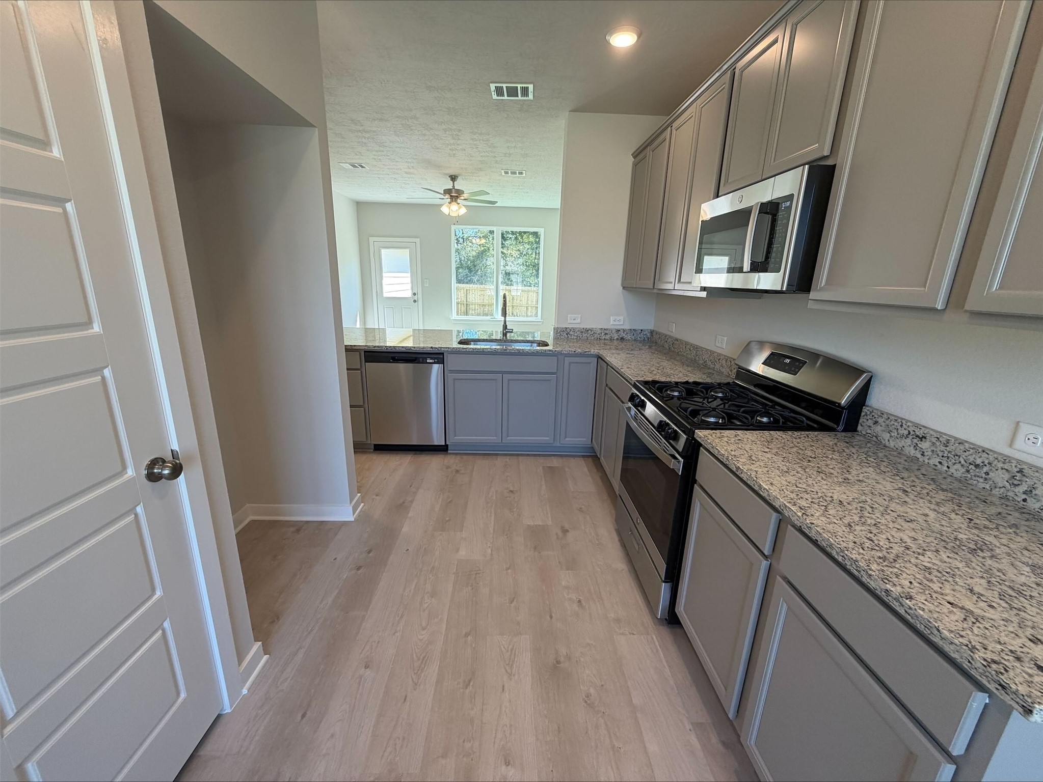 237 New Dawn Trail Huntsville, TX 77320 - Photo 5 of 23 a kitchen with a sink a microwave a stove and refrigerator