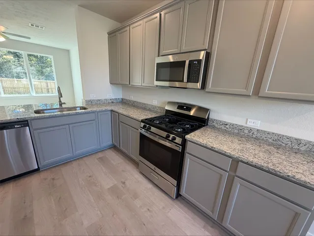 a kitchen with granite countertop stainless steel appliances a sink stove and microwave