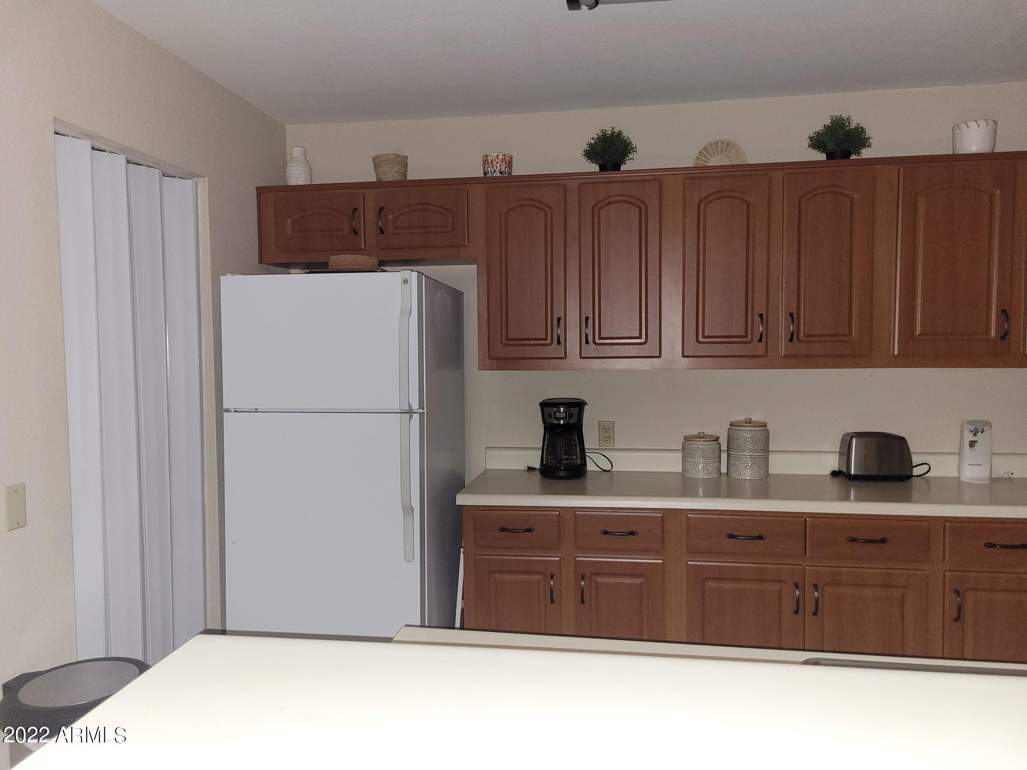 14300 West Bell Road, Unit 513 Surprise, AZ 85374 - Photo 12 of 23 a kitchen with a refrigerator and cabinets