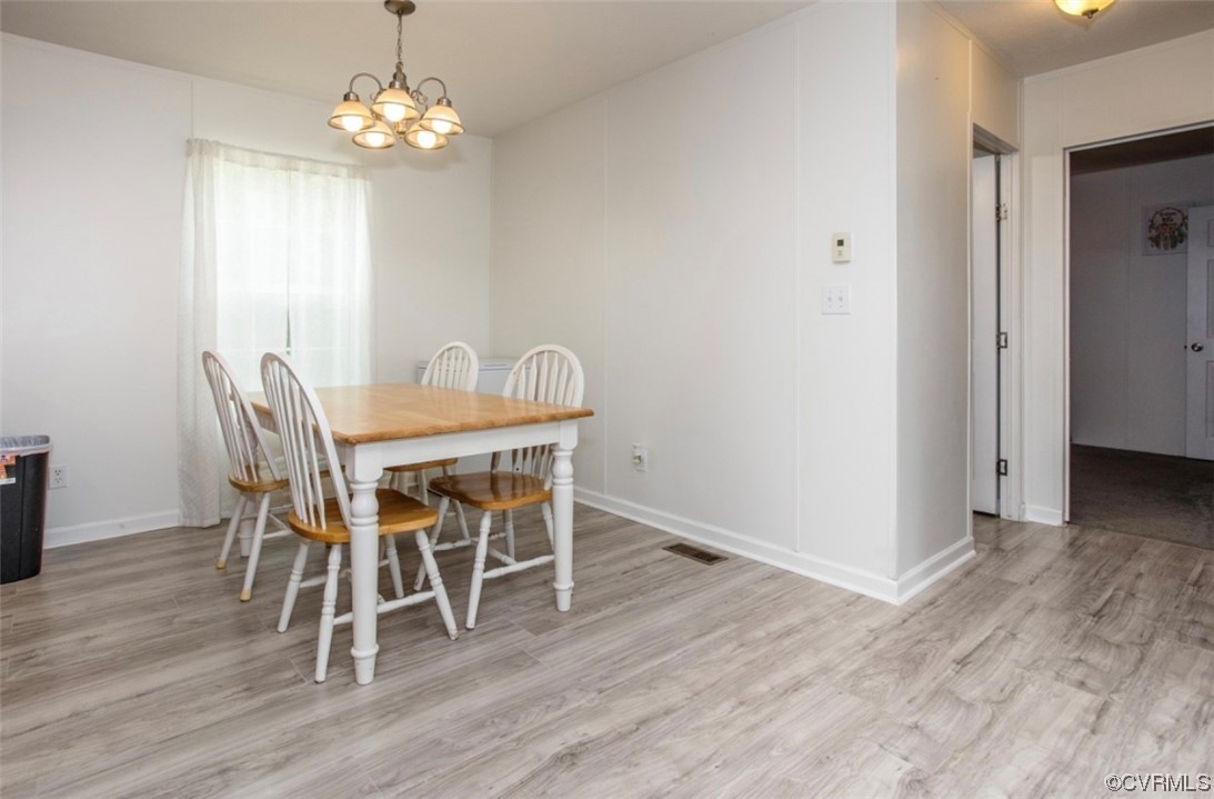 6302 Grubby Road Wilsons, VA 23894 - Photo 6 of 19 a dining room with wooden floor a chandelier a wooden table and chairs
