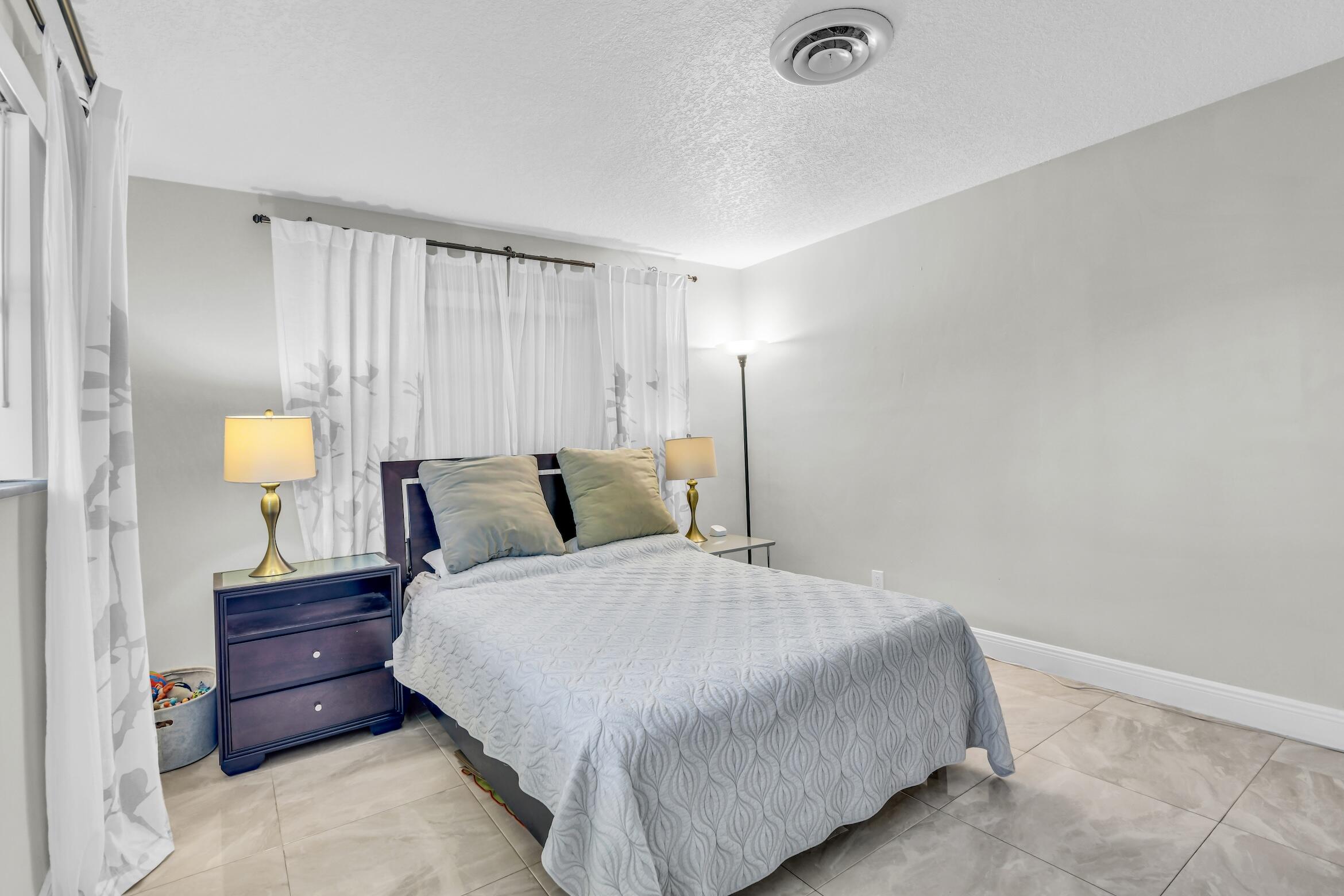 1290 Southwest 8th Street Boca Raton, FL 33486 - Photo 24 of 36 a bedroom with a bed and lamps
