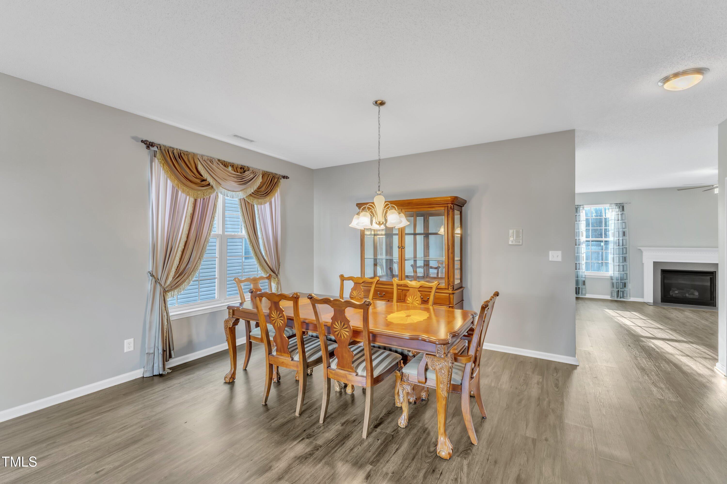 3408 Dutchman Road Raleigh, NC 27610 - Photo 12 of 54 a dining room with furniture a fireplace and wooden floor