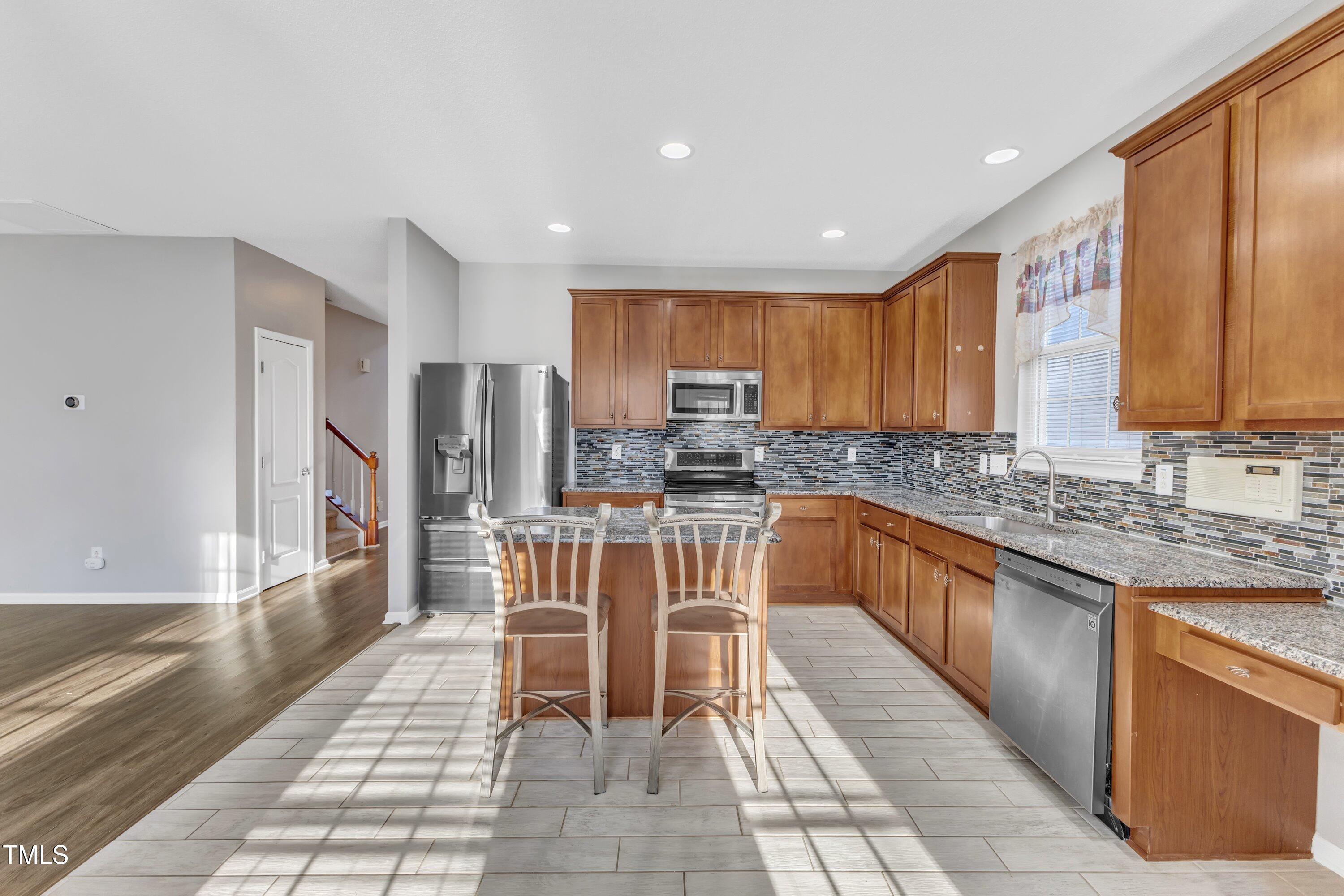 3408 Dutchman Road Raleigh, NC 27610 - Photo 24 of 54 a kitchen with stainless steel appliances granite countertop wooden cabinets a sink a stove a dining table and chairs