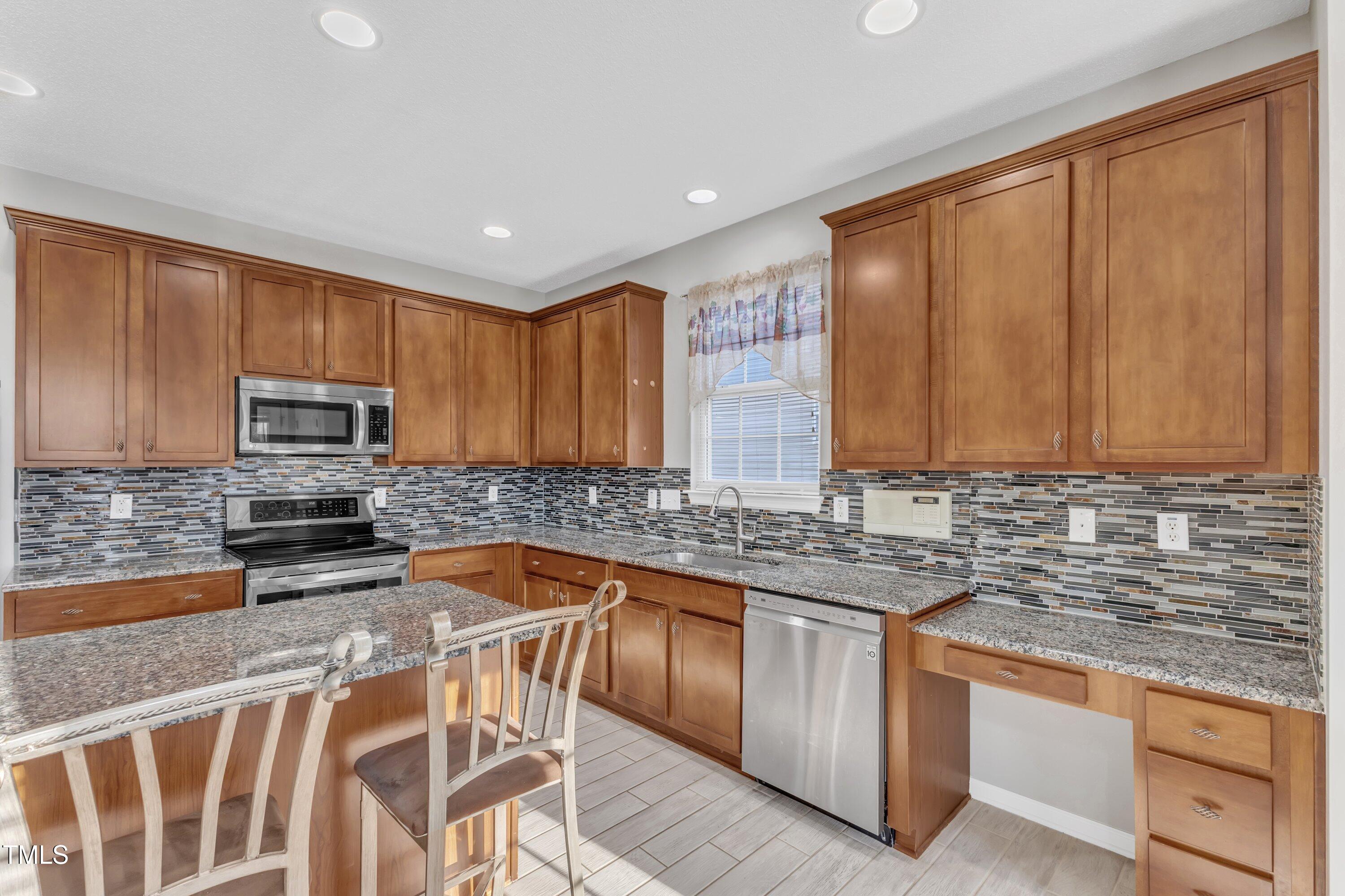 3408 Dutchman Road Raleigh, NC 27610 - Photo 25 of 54 a kitchen with stainless steel appliances granite countertop a stove top oven a sink dishwasher a dining table and chairs with wooden floor