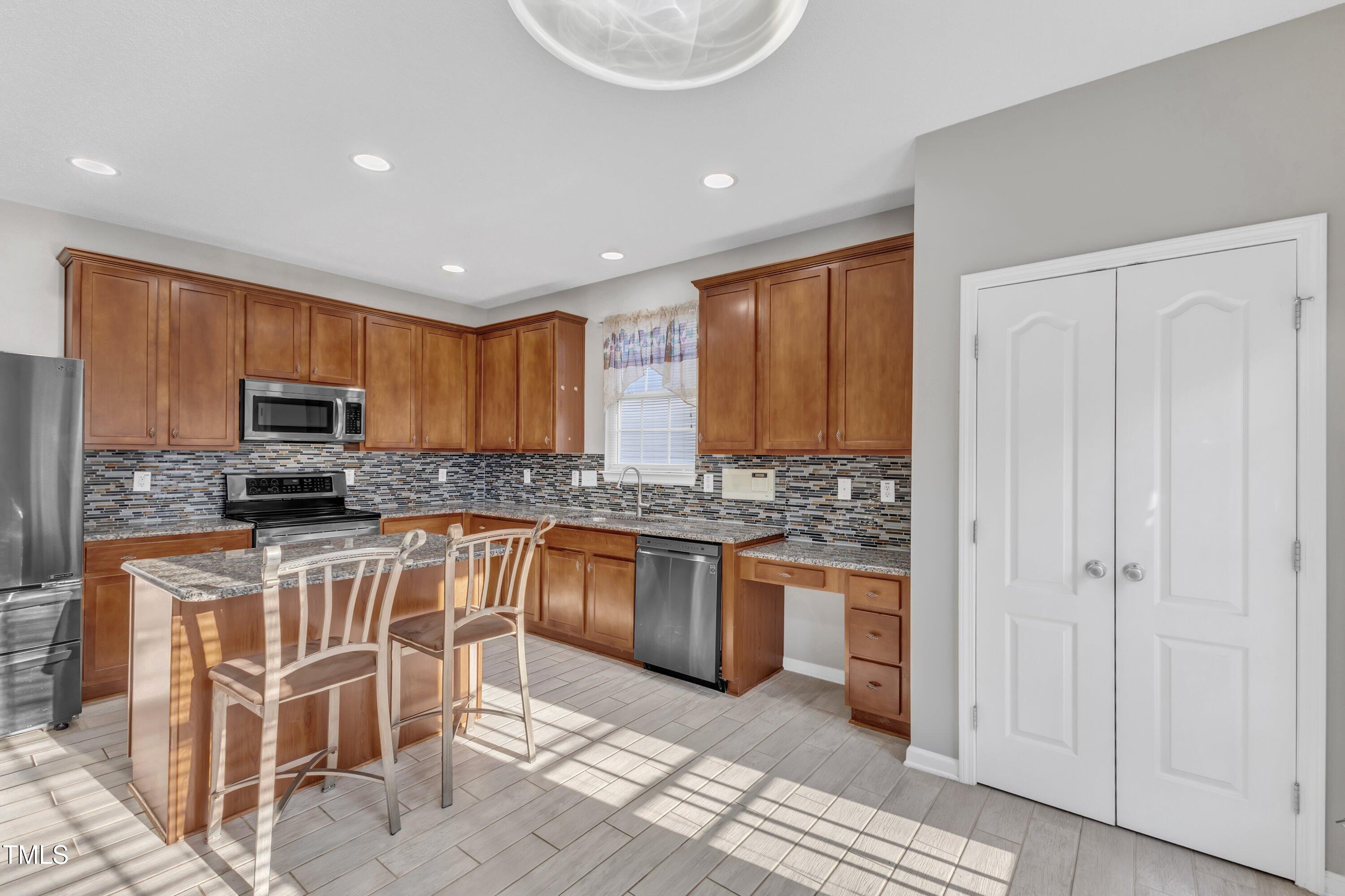 3408 Dutchman Road Raleigh, NC 27610 - Photo 30 of 54 a kitchen with stainless steel appliances granite countertop a stove top oven a sink dishwasher and a refrigerator with wooden floor