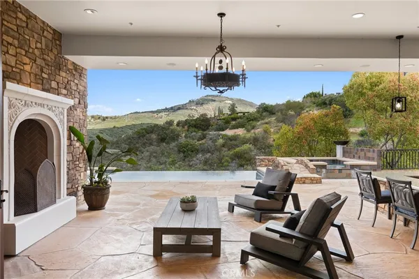 a living room with couches a fireplace and kitchen view with wooden floor