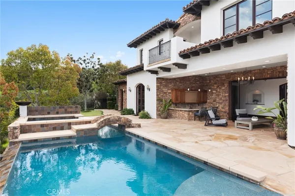 a view of a patio with couches fire pit and a barbeque grill with plants and large trees