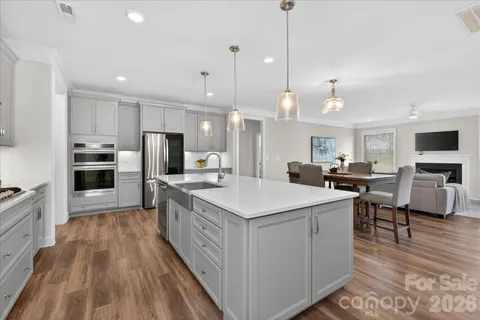 a large kitchen with kitchen island a stove a sink a refrigerator and a dining table with wooden floor