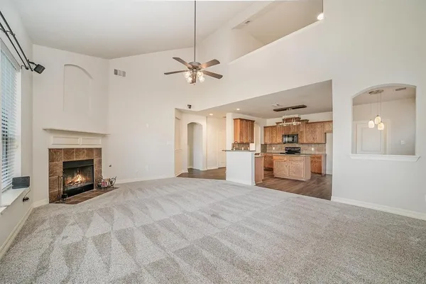a view of empty room with kitchen and fireplace