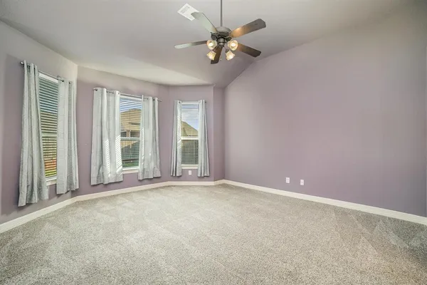an empty room with windows and ceiling fan