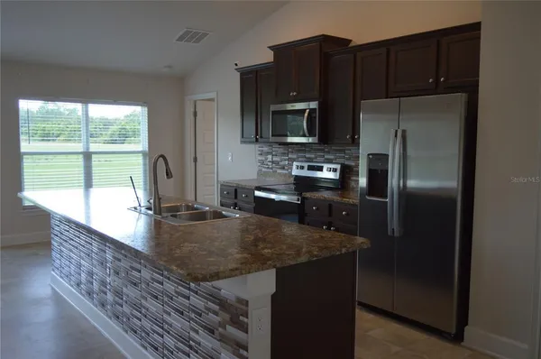 a kitchen with kitchen island a counter top space a sink stainless steel appliances and a window
