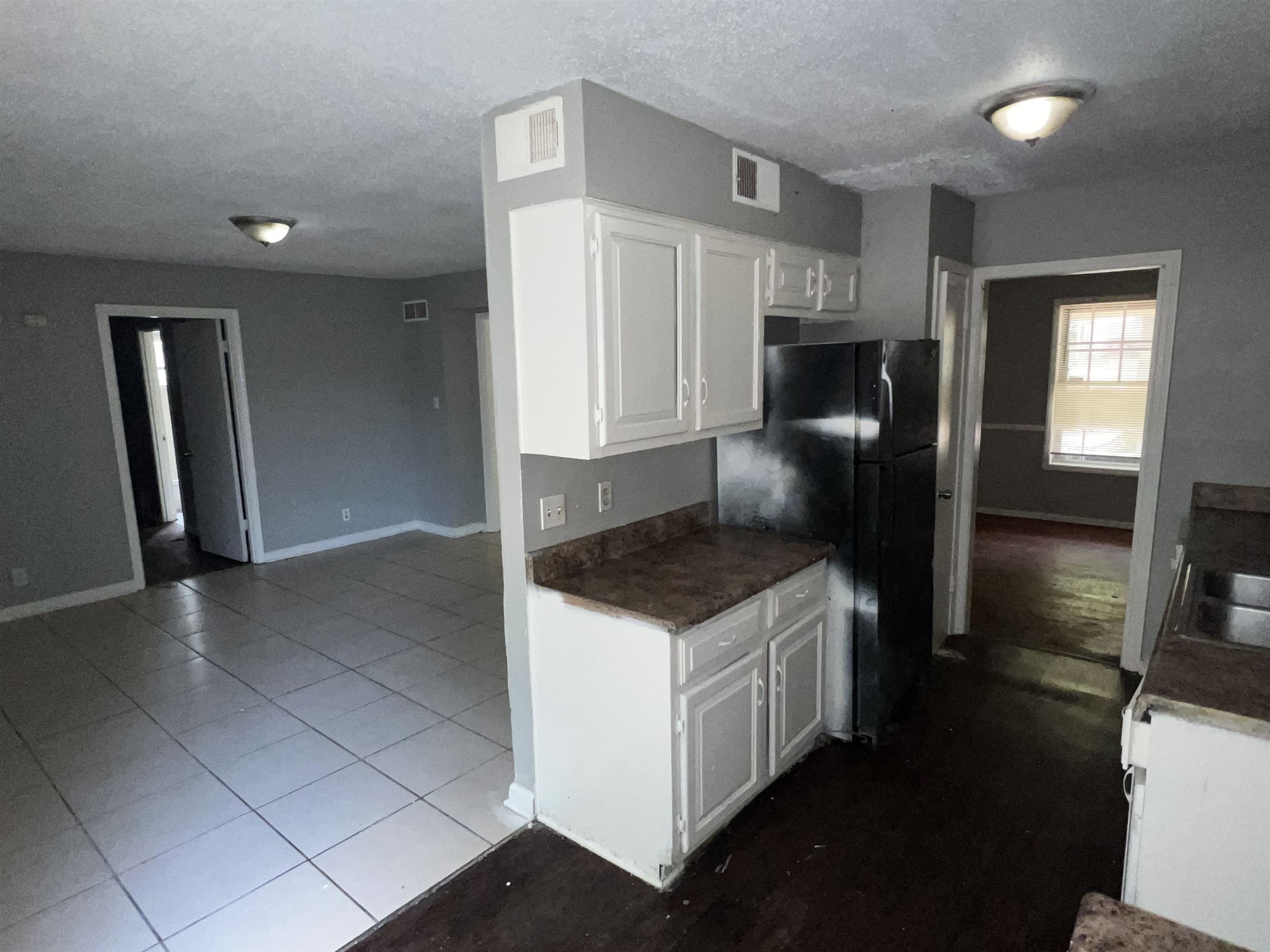 2950 Invergarry Road Memphis, TN 38128 - Photo 4 of 19 Kitchen with white cabinets, tile patterned floors, black fridge, and a textured ceiling