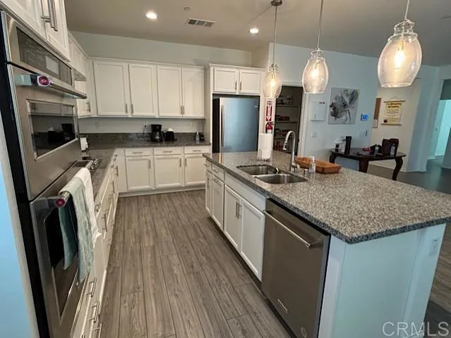 a kitchen with stainless steel appliances granite countertop a sink a stove a refrigerator and cabinets