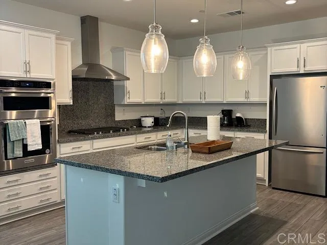 a kitchen with stainless steel appliances granite countertop a sink a stove a refrigerator a center island and cabinets