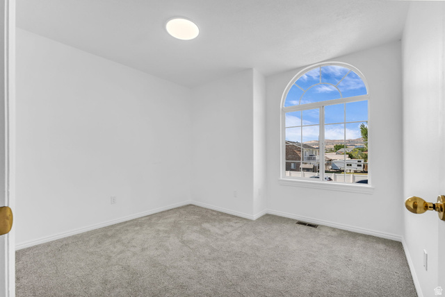 1147 West State Road Lehi, UT 84043 - Photo 23 of 31 Room featuring an arched window with grid detailing, neutral carpeting, white walls, and a ceiling-mounted light fixture