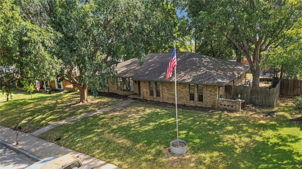 1320 Cheyenne Road Lewisville, TX 75077 - Photo 2 of 27 Brick exterior featuring a gabled roof and mature trees
