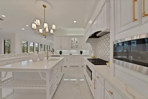 a kitchen with stainless steel appliances a stove a sink and white cabinets