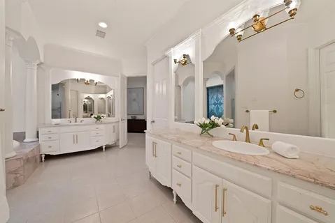 a bathroom with a double vanity sink mirror and bathtub