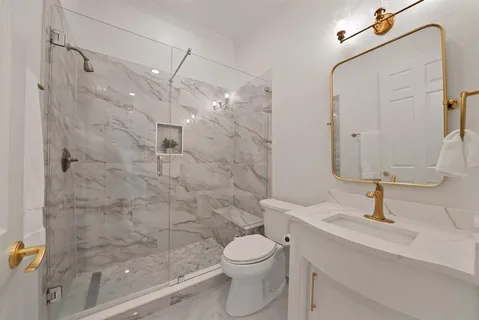 a bathroom with a granite countertop sink a toilet and shower