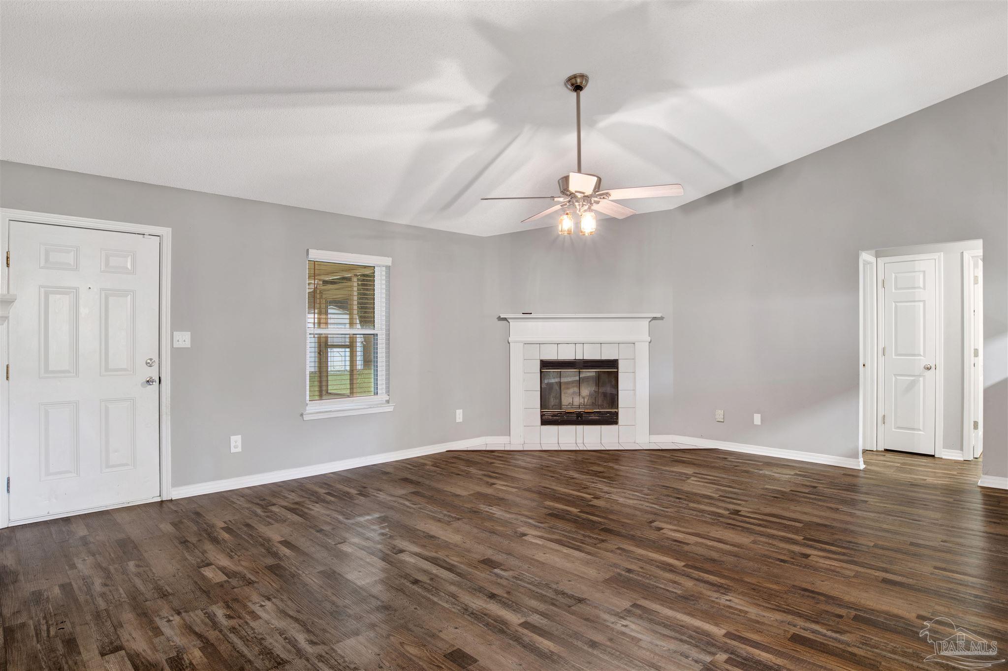 5801 Loring Drive Milton, FL 32583 - Photo 3 of 27 a view of empty room with wooden floor fireplace and window